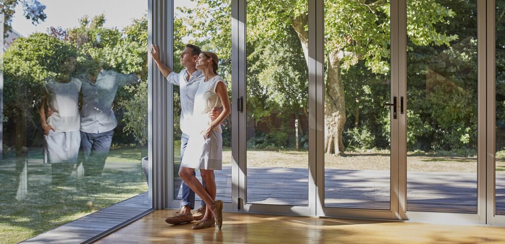 Full length of loving mid adult couple looking through glass window