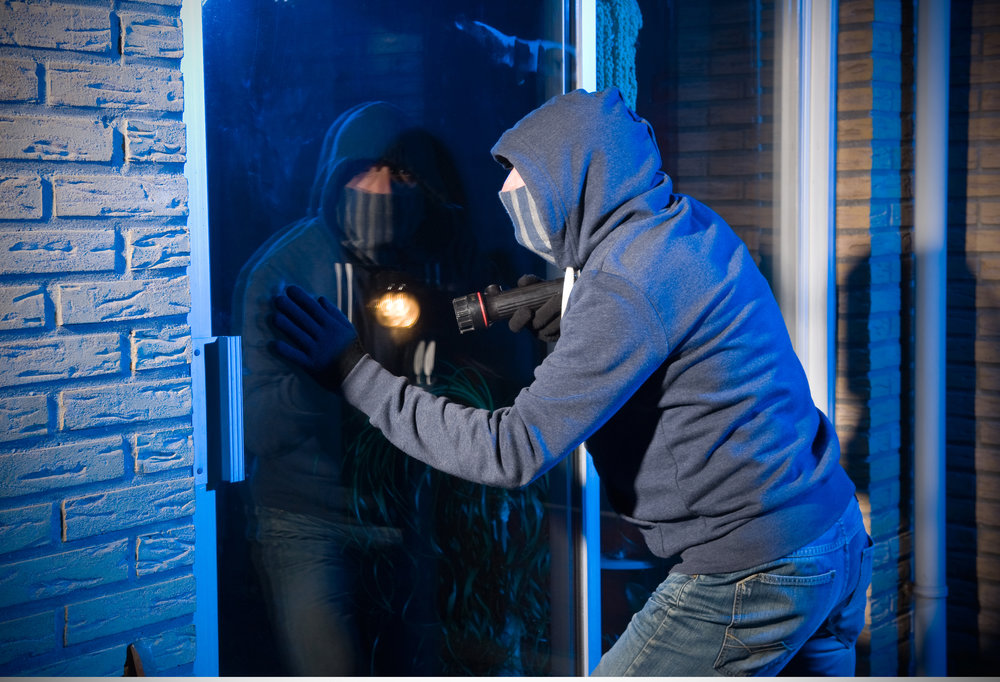 image of a burglar attempting to break a glass